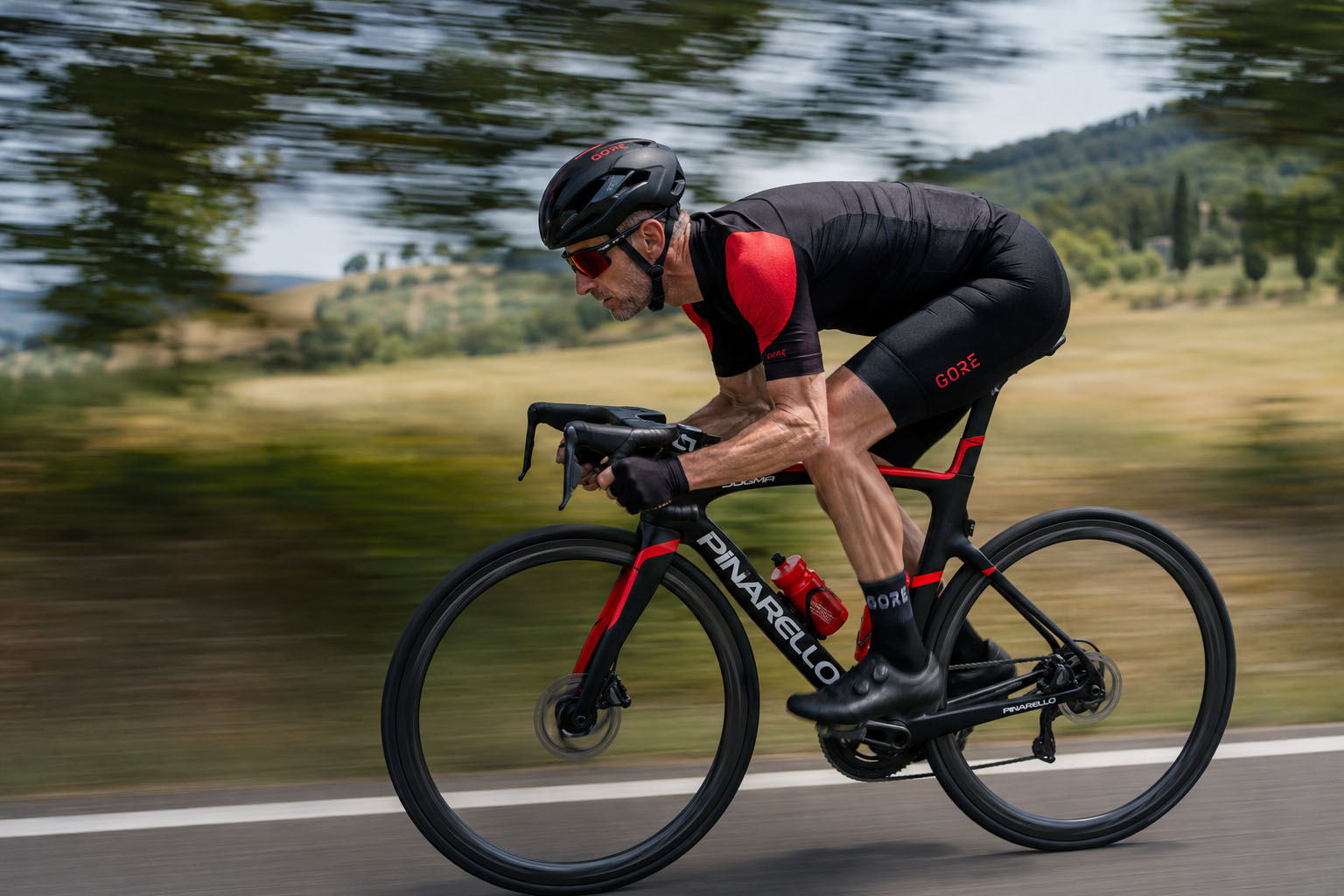Cycliste de profil sur une route asphaltée, maintenant une position dos plat ultra aérodynamique